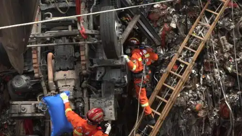 一垃圾车坠入14米深坑,消防万吨垃圾中搭梯救人